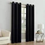 Two black blackout curtains hang on a window, blocking out sunlight