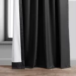 black blackout curtain hanging on a window. The curtain has a subtle sheen and appears to be made of a thick, woven fabric