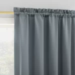 dark gray blackout curtain with a subtle texture hangs neatly on a rod