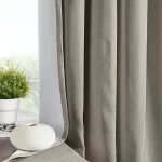 soft gray blackout curtains hang on a window. The curtains have a subtle texture and a white lining is visible along the edges